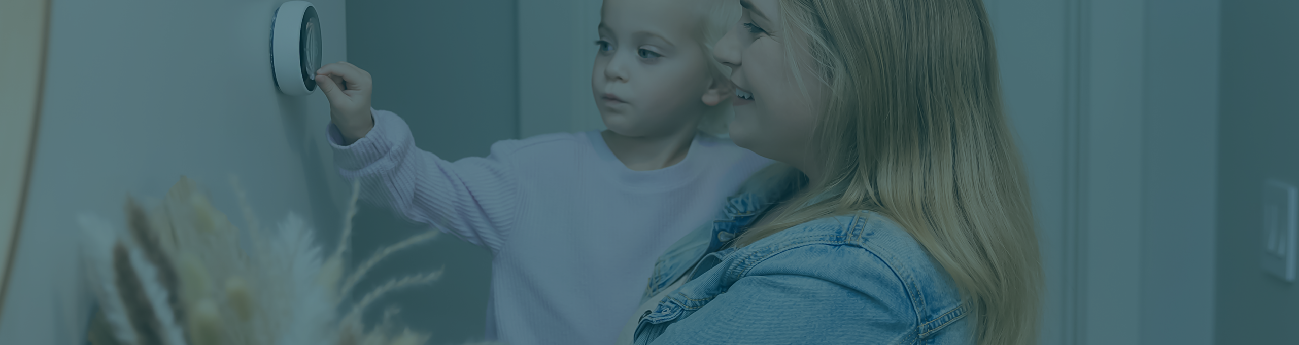 Woman and child adjusting a thermostat for a load flexibility program